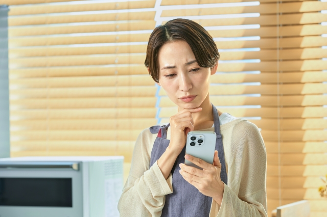 スマホを見て悩む女性