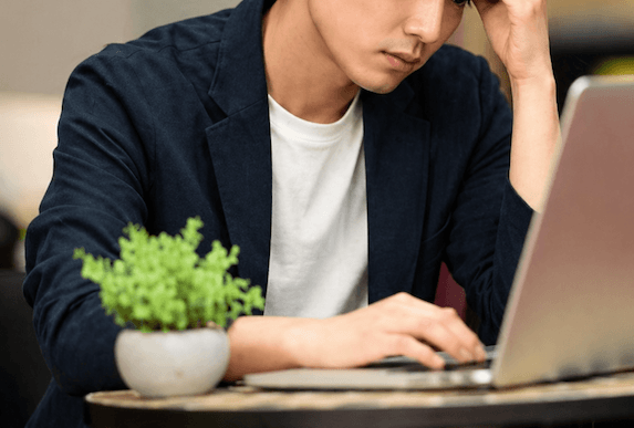 PCの前で悩む若い男性