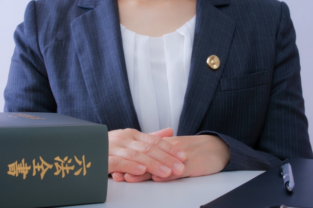 六法全書の前で手を組む女性弁護士