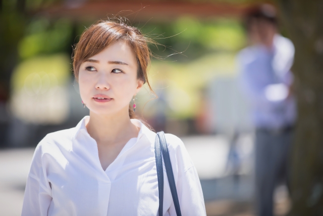 道を歩く女性の背後に男性の影