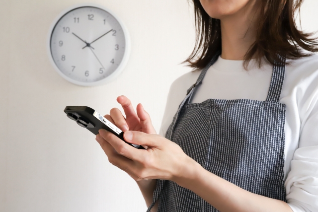スマホを操作するエプロン姿の女性